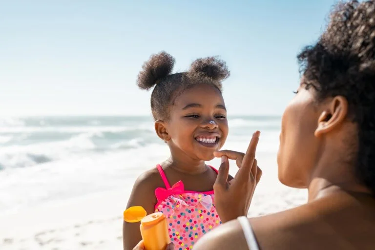 mom putting suntan lotion on her small daughter