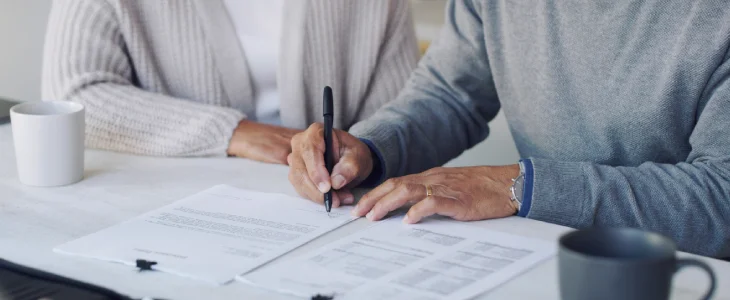 an elderly couple signing documentation